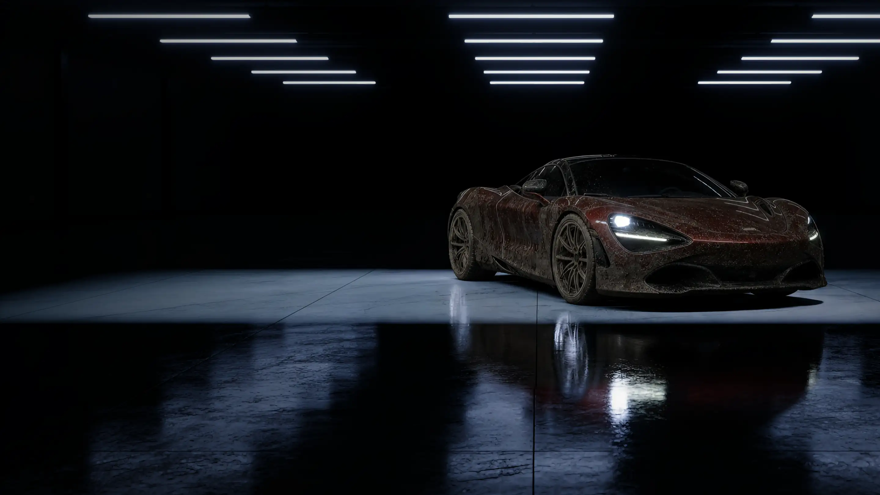 A mud-covered red sports car in a dark detailing bay